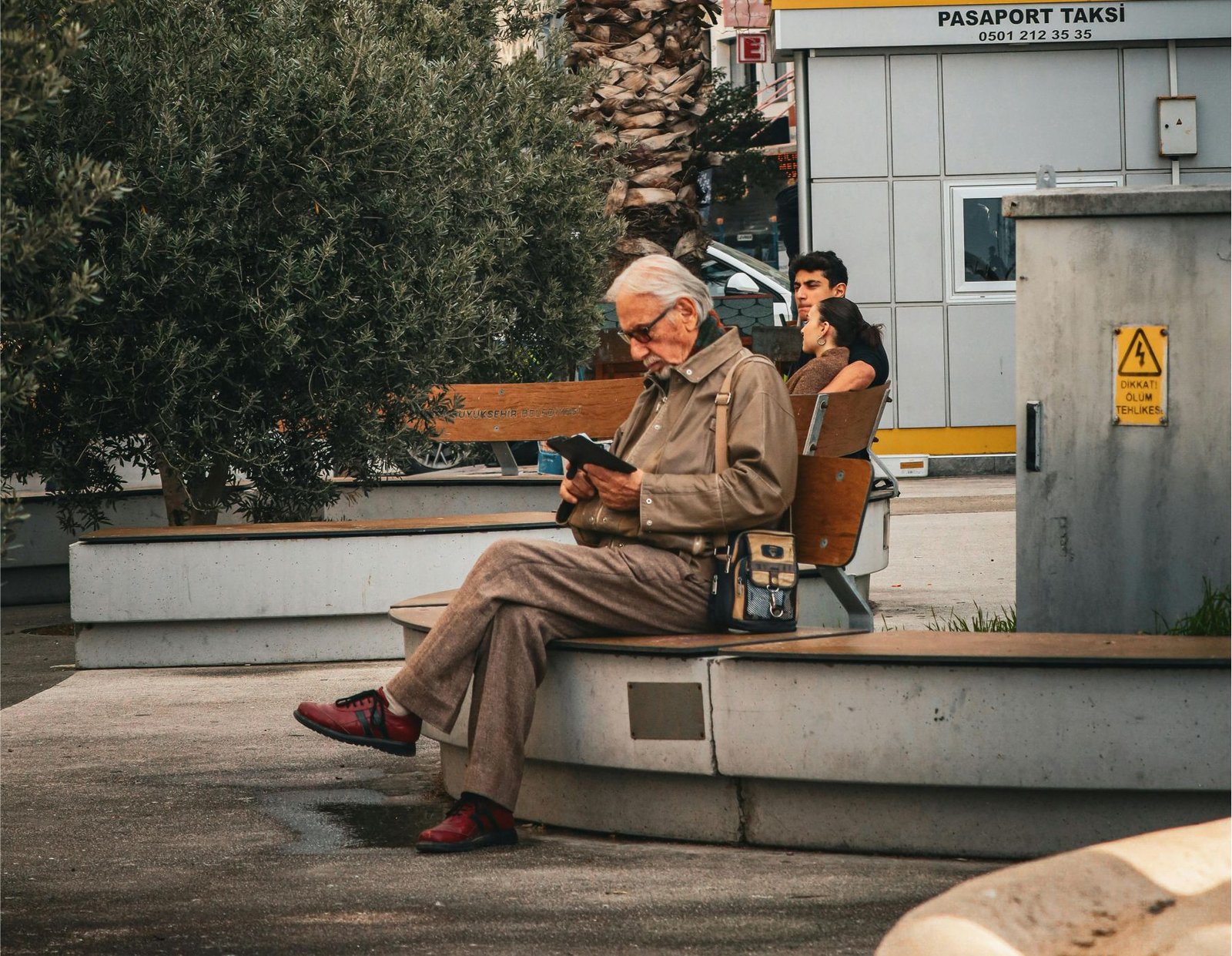 Adulto leyendo un libro en la calle en una banca 