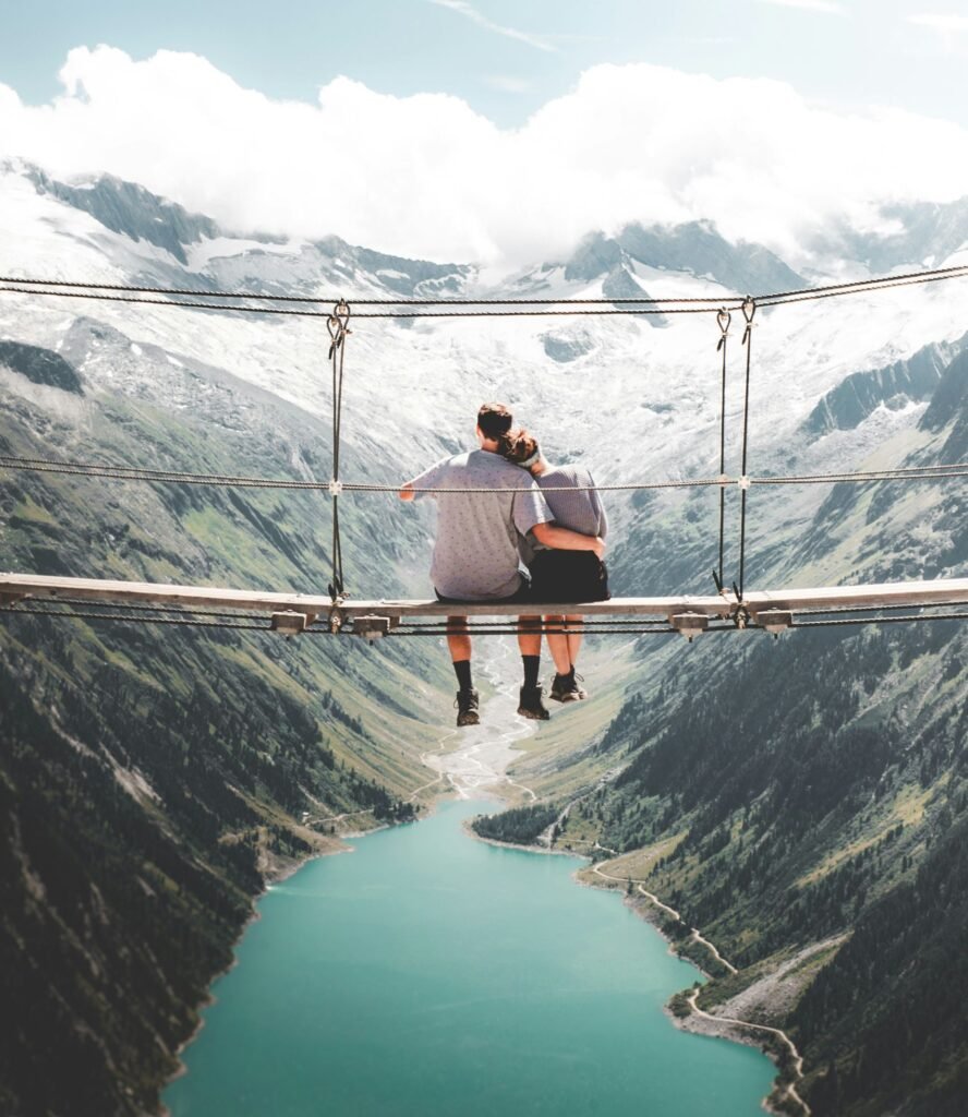 Pareja sentadas en un puente colgante disfrutando de la vista