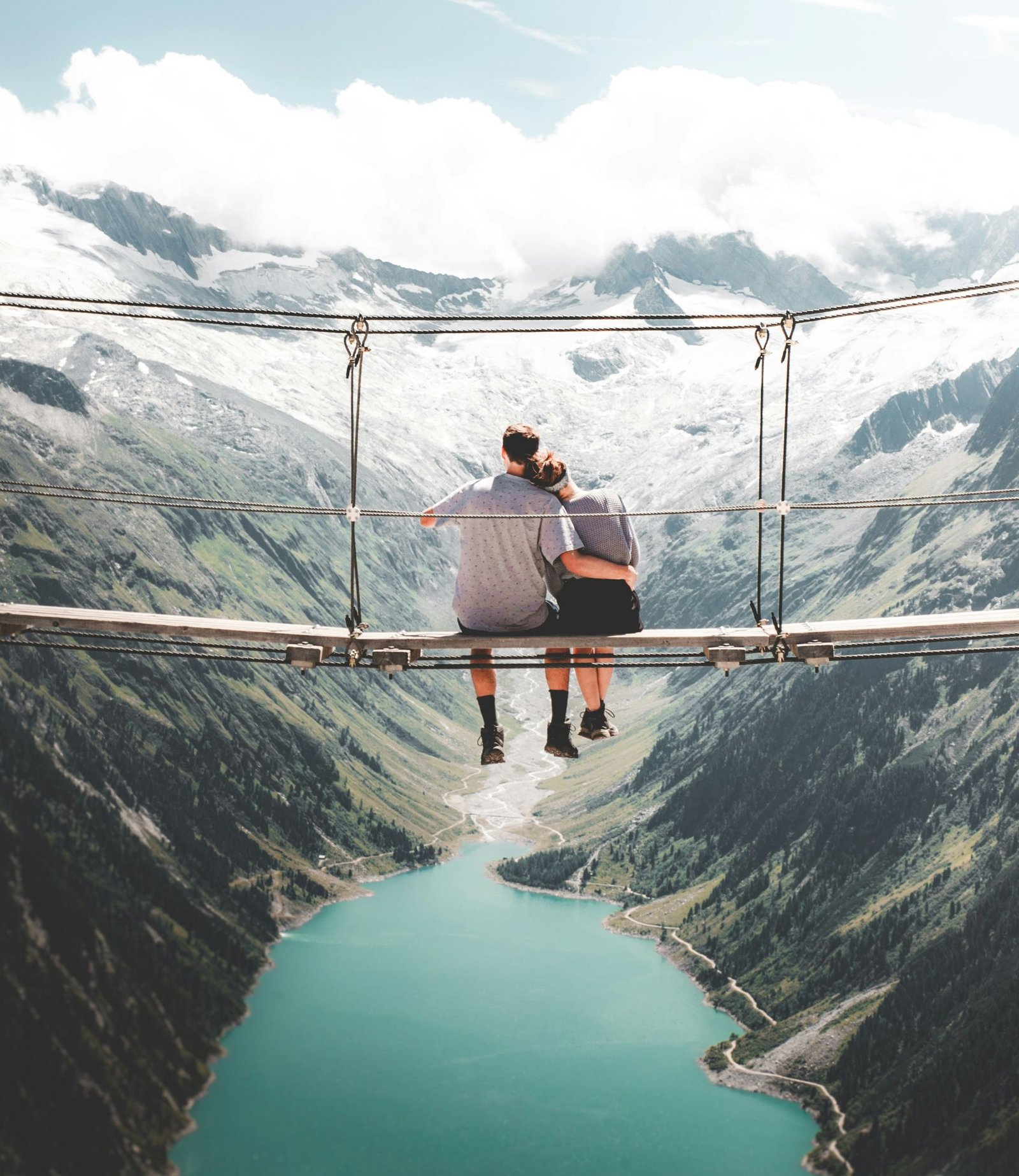 Pareja sentadas en un puente colgante disfrutando de la vista